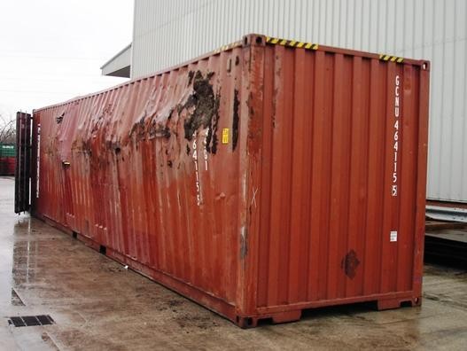 Damaged shipping container with severe dents and corrosion, illustrating structural wear that can affect container-based construction projects